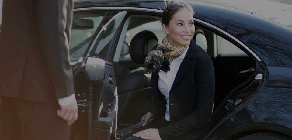 A happy business woman stepping out of the limousine with a briefcase